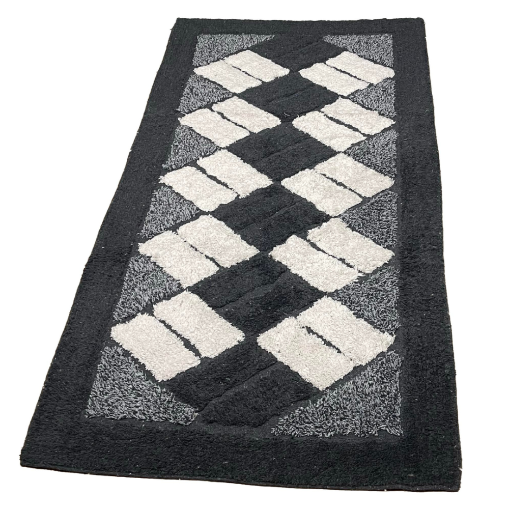 Teppich „Black Diamond Mosaic Rug“, 70x140 cm. Schwarzer teppich, verziert mit cremefarbenen rechtecken in dynamischen diagonalen reihen.